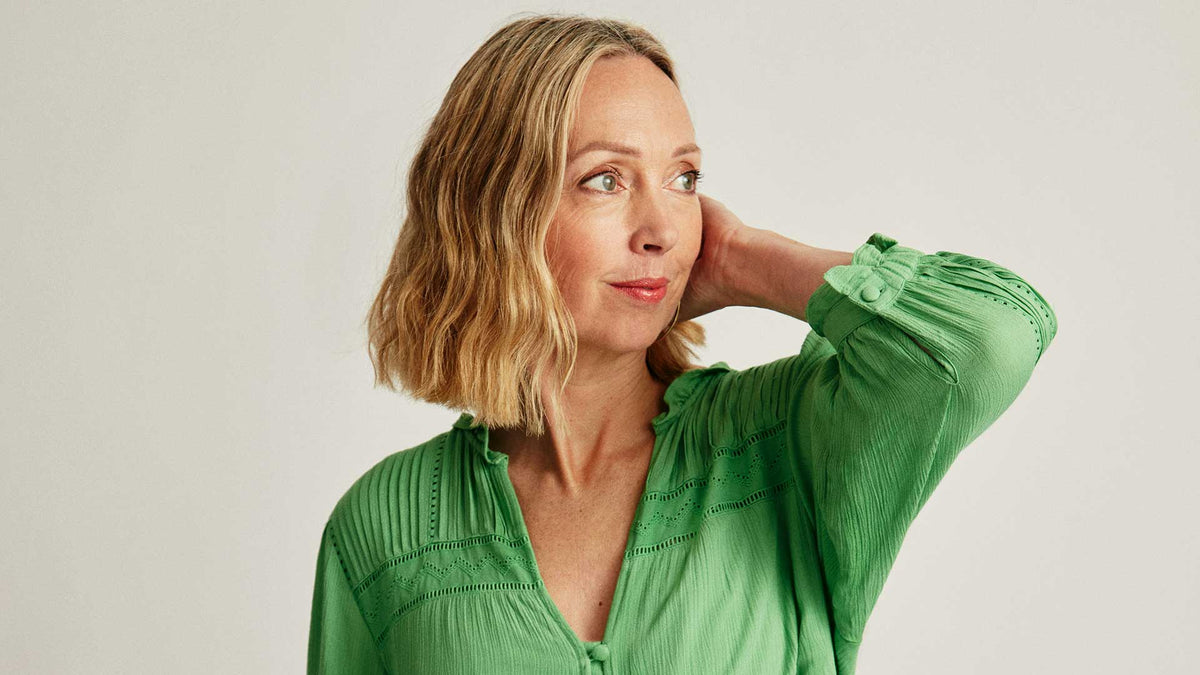 Image of older woman in green dress with hand near head